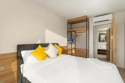 a bedroom with a large white bed with yellow pillows at Laguna LakeSide Residences by My Home Phuket in Bang Tao Beach