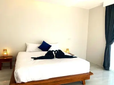 a bedroom with a white bed with blue curtains at GOODNIGHT Hill KOHYAOYAI in Ban Nai Wat