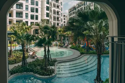 a view of a pool with palm trees and buildings at Title Legendary Apartment 800m to Bang Tao Beach in Bang Tao Beach