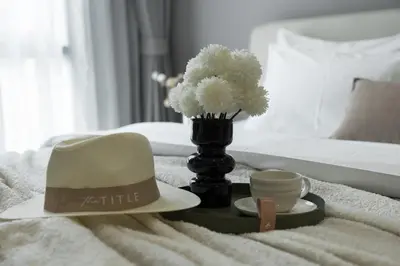 a hat and a cup and a vase with flowers on a bed at Title Legendary Apartment 800m to Bang Tao Beach in Bang Tao Beach