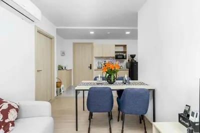 a living room with a dining room table with blue chairs at C262 Relax 2BR Condo with Pool and Full Gym in Kathu