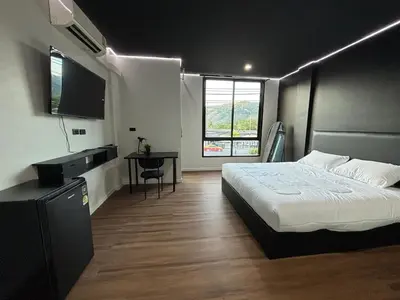 a bedroom with a bed and a flat screen tv at Atrium Kathu Hotel in Ban Kathu