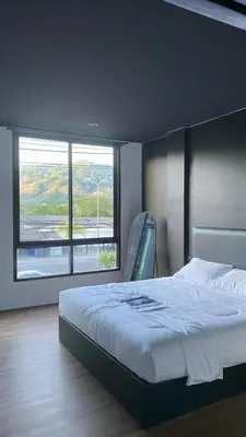 a bedroom with a bed and a large window at Atrium Kathu Hotel in Ban Kathu