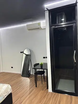 a room with a table and a black refrigerator at Atrium Kathu Hotel in Ban Kathu
