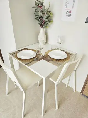 a white dining room table with two chairs and a vase with flowers at patong see view condo in Patong Beach