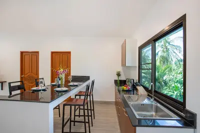 a kitchen with a counter and a large window at Large Private Pool 5BR Villa Tony near Promthep Cape in Nai Harn Beach