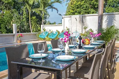 a long table with chairs and wine glasses on a patio at Large Private Pool 5BR Villa Tony near Promthep Cape in Nai Harn Beach