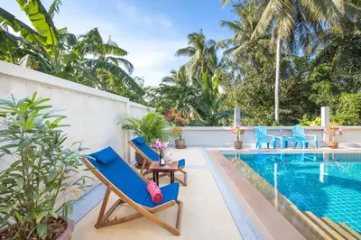 a pool with blue lounge chairs next to a swimming pool at Large Private Pool 5BR Villa Tony near Promthep Cape in Nai Harn Beach