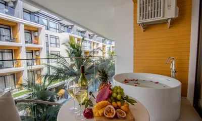 a bathroom with a tub and a table with fruit and wine glasses at One Bedroom Wyndham Naithon with Jacuzzi in Phuket Town