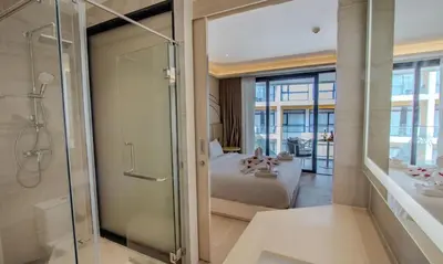 a bathroom with a shower and a bedroom with a bed at One Bedroom Wyndham Naithon with Jacuzzi in Phuket Town