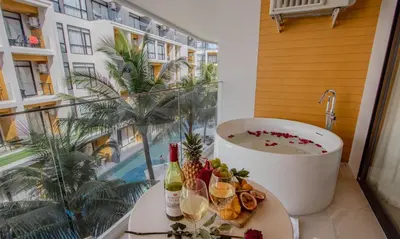 a bathroom with a tub and a table with wine glasses at One Bedroom Wyndham Naithon with Jacuzzi in Phuket Town