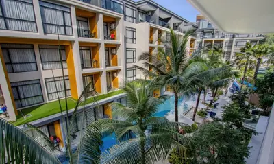 an apartment building with a swimming pool and palm trees at One Bedroom Wyndham Naithon with Jacuzzi in Phuket Town