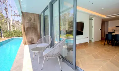 a house with a swimming pool and a table and chairs at Kora 77 2BR Beachfront Condo with Sea View and Pool in Phuket Town