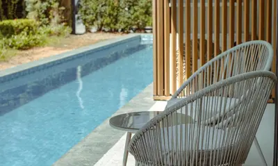 a chair and a table next to a swimming pool at Kora 77 2BR Beachfront Condo with Sea View and Pool in Phuket Town