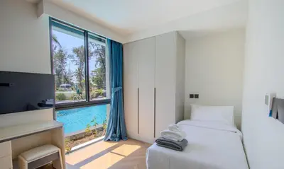 a bedroom with a bed and a window with a pool at Kora 77 2BR Beachfront Condo with Sea View and Pool in Phuket Town