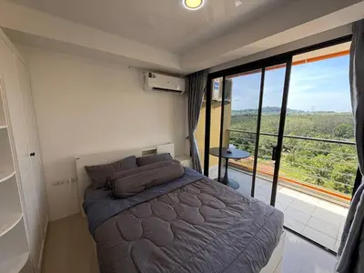 a bedroom with a bed and a large window at FAMILY HOMES Mai Khao Poolside Studio CB-845 Near Sirinat Park in Ban Mai Salae