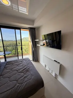 a bedroom with a bed and a tv and a balcony at FAMILY HOMES Mai Khao Poolside Studio CB-845 Near Sirinat Park in Ban Mai Salae