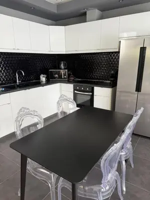 a kitchen with a black table and white cabinets at Villa DIAZ RAWAI in Ban Saiyuan (1)