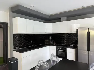 a kitchen with white cabinets and a black counter top at Villa DIAZ RAWAI in Ban Saiyuan (1)