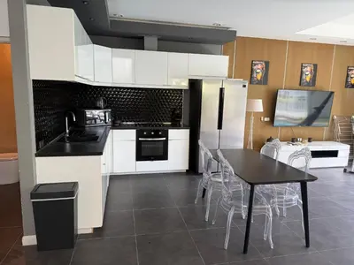 a kitchen with white appliances and a table and chairs at Villa DIAZ RAWAI in Ban Saiyuan (1)