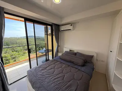 a bedroom with a bed and a large window at The Signature Studio at Mai Khao by FAMILY HOMES CB-846 in Ban Mai Salae