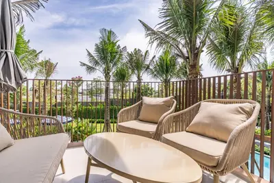 a patio with chairs and tables and palm trees at Canvas Apartments in Laguna Phuket