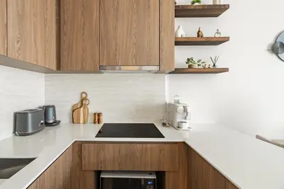 a kitchen with white counter tops and wooden cabinets at Canvas Apartments in Laguna Phuket