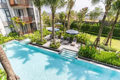 a swimming pool with chairs and umbrellas next to a building at Canvas Apartments in Laguna Phuket