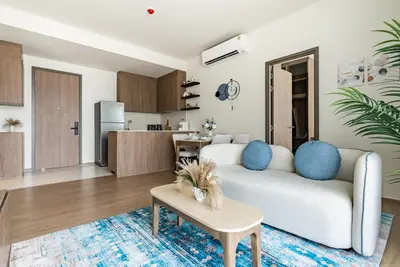 a living room with a white couch and a kitchen at Canvas Apartments in Laguna Phuket