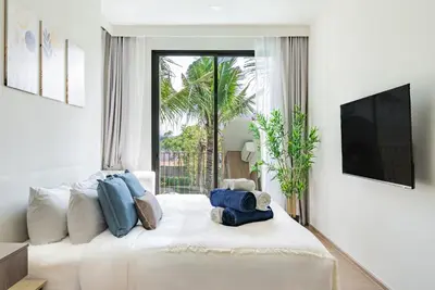 a bedroom with a large white bed with blue pillows at Canvas Apartments in Laguna Phuket