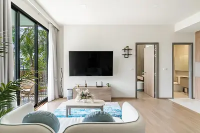 a living room with a tv on a wall at Canvas Apartments in Laguna Phuket