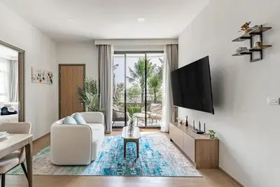 a living room with a tv on a wall at Canvas Apartments in Laguna Phuket