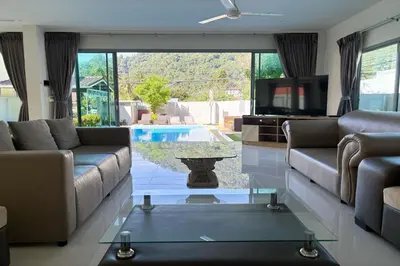 a living room with a couch and a tv and a table at Grand Villa Ishu 4BR Private Pool in Kamala Beach