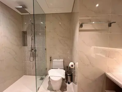 a bathroom with a toilet and a glass shower at Cassia Residences Condo in Laguna Phuket in Laguna Phuket