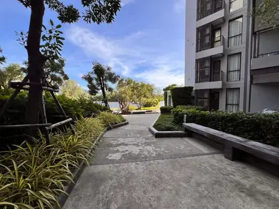 a walkway in front of a building with a bench at Cassia Residences Condo in Laguna Phuket in Laguna Phuket
