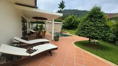 a patio with chairs and a tree and a house at Lai Thai Villa 4 in Rawai Beach