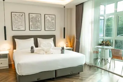 a bedroom with a large white bed with a heart pillow at Rawai Lalaland Studio Apartments in Ban Saiyuan (1)