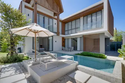 a house with a pool and an umbrella at New 4 bedroom villa 700 meters to Bang Tao Beach in Ban Thalat Choeng Thale