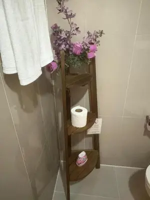 a bathroom with a shelf with a toilet and flowers at Sunny The Deck Patong Apartment in Patong Beach