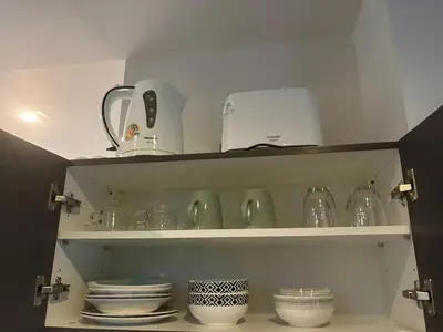 a kitchen shelf with dishes and glass items on it at Sunny The Deck Patong Apartment in Patong Beach