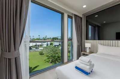a bedroom with a bed and a large window at Suite Anafi 2BR Pool Gym Access Ozone in Laguna Phuket