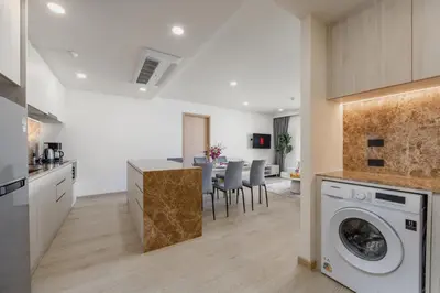 a kitchen and living room with a washer and dryer at Suite Anafi 2BR Pool Gym Access Ozone in Laguna Phuket