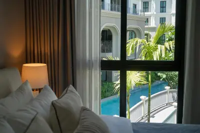 a bedroom with a view of a pool through a window at Luxury 2 bdr Title Legendary Bang Tao Pool View in Bang Tao Beach