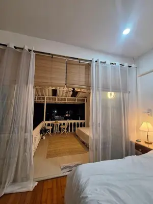 a bedroom with white curtains and a bed in a room at The Lighthouse Seaview Hotel in Rawai Beach