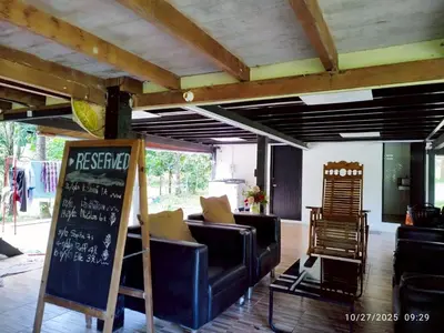 a living room with couches and a chalkboard on the floor at Suan Tha-Thong Homestay in Ban Bang Pla