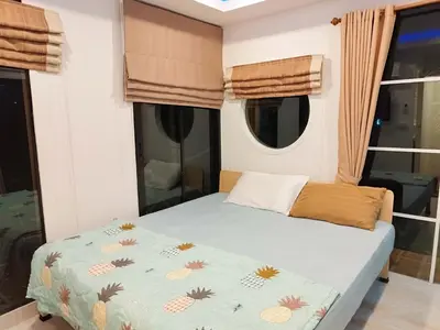 a bedroom with a bed with a blue comforter and windows at Suan Tha-Thong Homestay in Ban Bang Pla