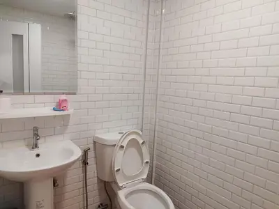 a white bathroom with a toilet and a sink at Suan Tha-Thong Homestay in Ban Bang Pla