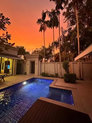 a swimming pool in front of a house with a sunset at 4-Bedroom cozy pool villa in the heart of Bang Tao in Laguna Phuket