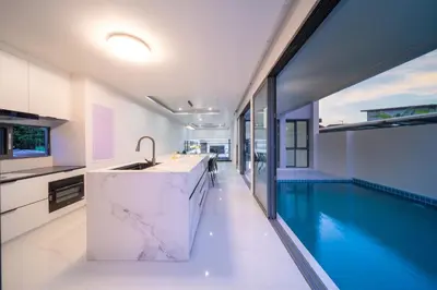 a kitchen with a swimming pool next to a house at BangTao 5 Bedrooms 2026 New Modern Private Pool Villa Great Location Close to Bangtao Beach in Ban Thalat Choeng Thale