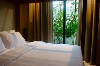 a bedroom with a bed and a window with a plant at Botanica Four Season Luxury Pool Villa in Phuket